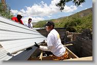 Rene Romil, a Haitian worker, along with Tru Pettigrew, right, and Christopher Yarboro, volunteers with the North Carolina Baptist Men Disaster Relief, help put the roof on as they build houses in Titanyen Haiti Monday May 3, 2010.   ETHAN HYMAN  - ehyman@newsobserver.com