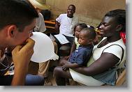 Stephen Winchell with ALERT blows up a glove balloon for Pierre Ginelson, 2, and his sister, Dival Naphtaline, 6, during a medical clinic by volunteers with the North Carolina Baptist Men Disaster Relief team in Cabaret, Haiti Friday May 7, 2010.  ETHAN HYMAN  - ehyman@newsobserver.com